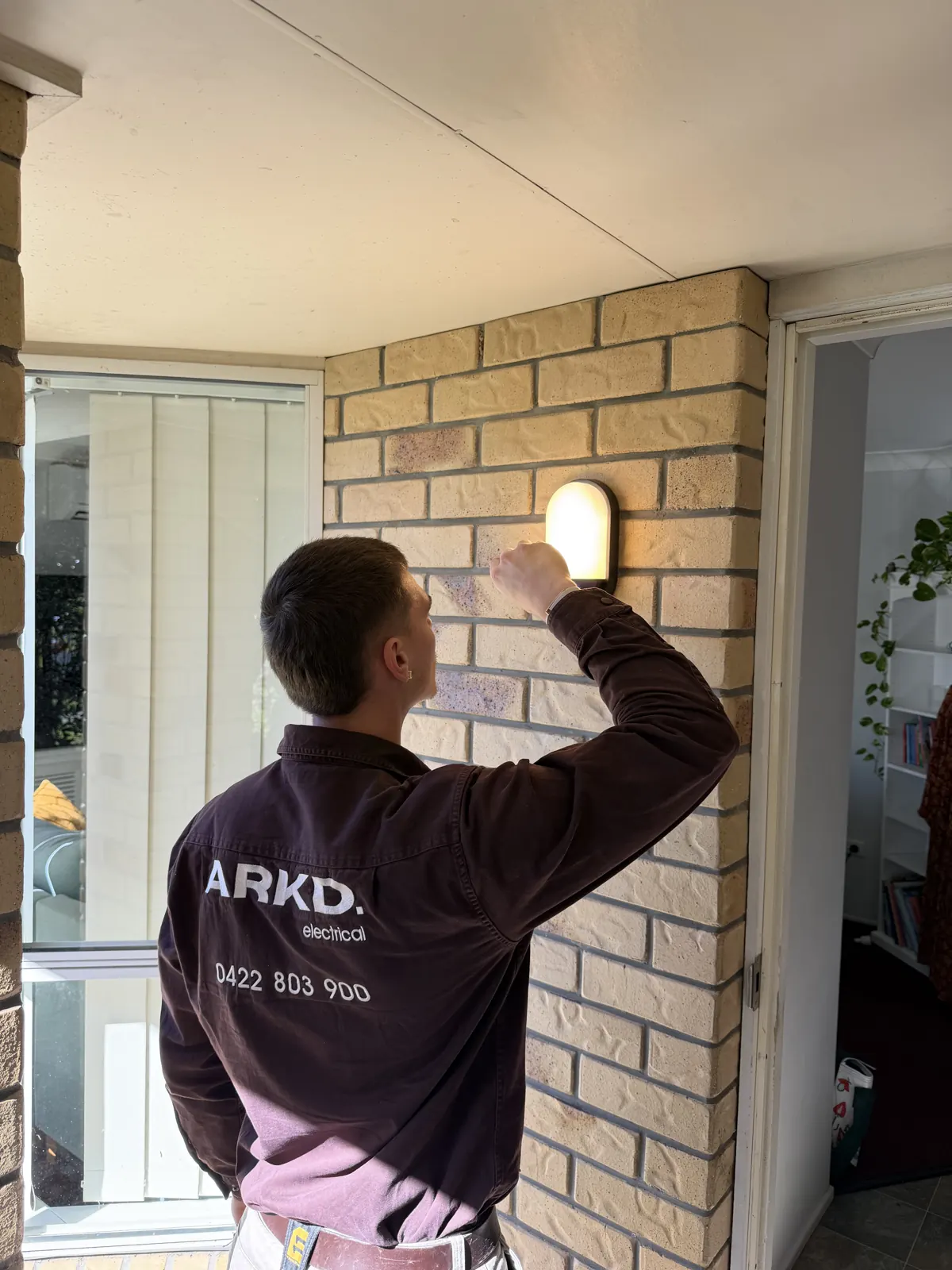 ARKD electrician servicing an exterior wall light at a Brisbane home