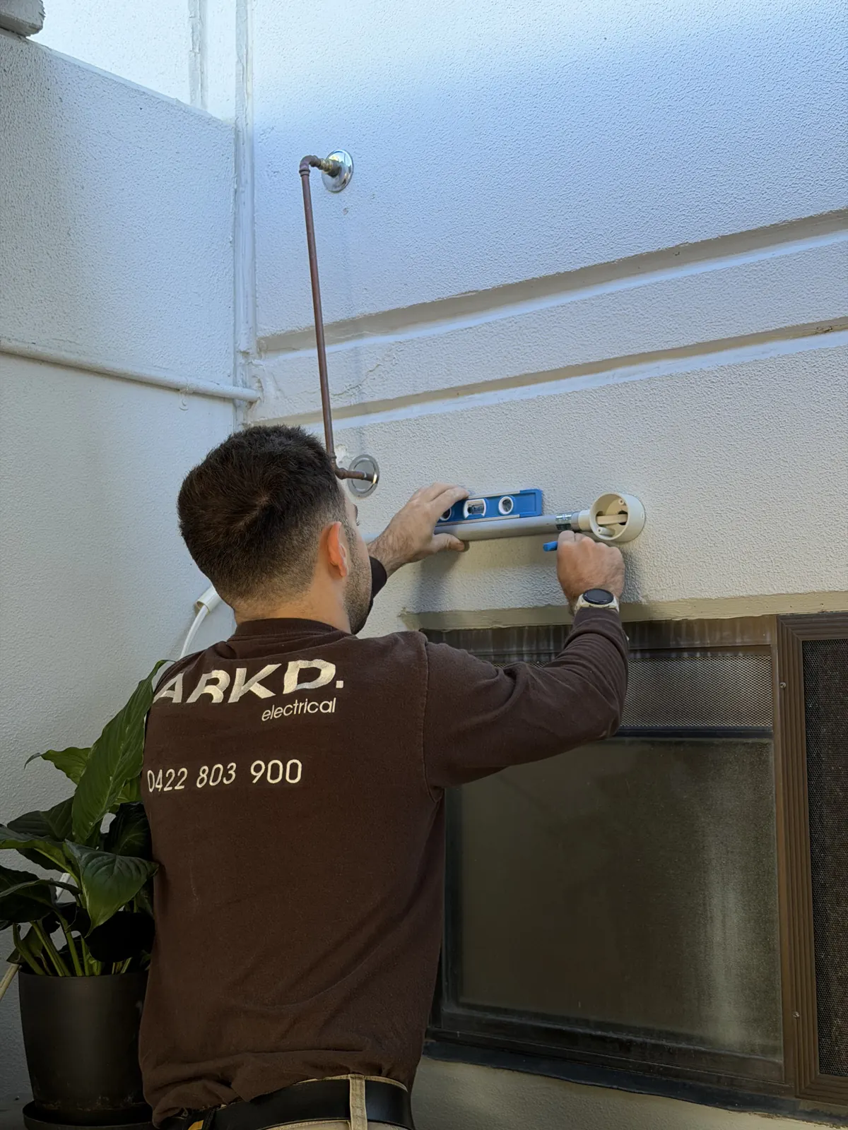 ARKD electrician installing an outdoor smart sensor light at a Brisbane home