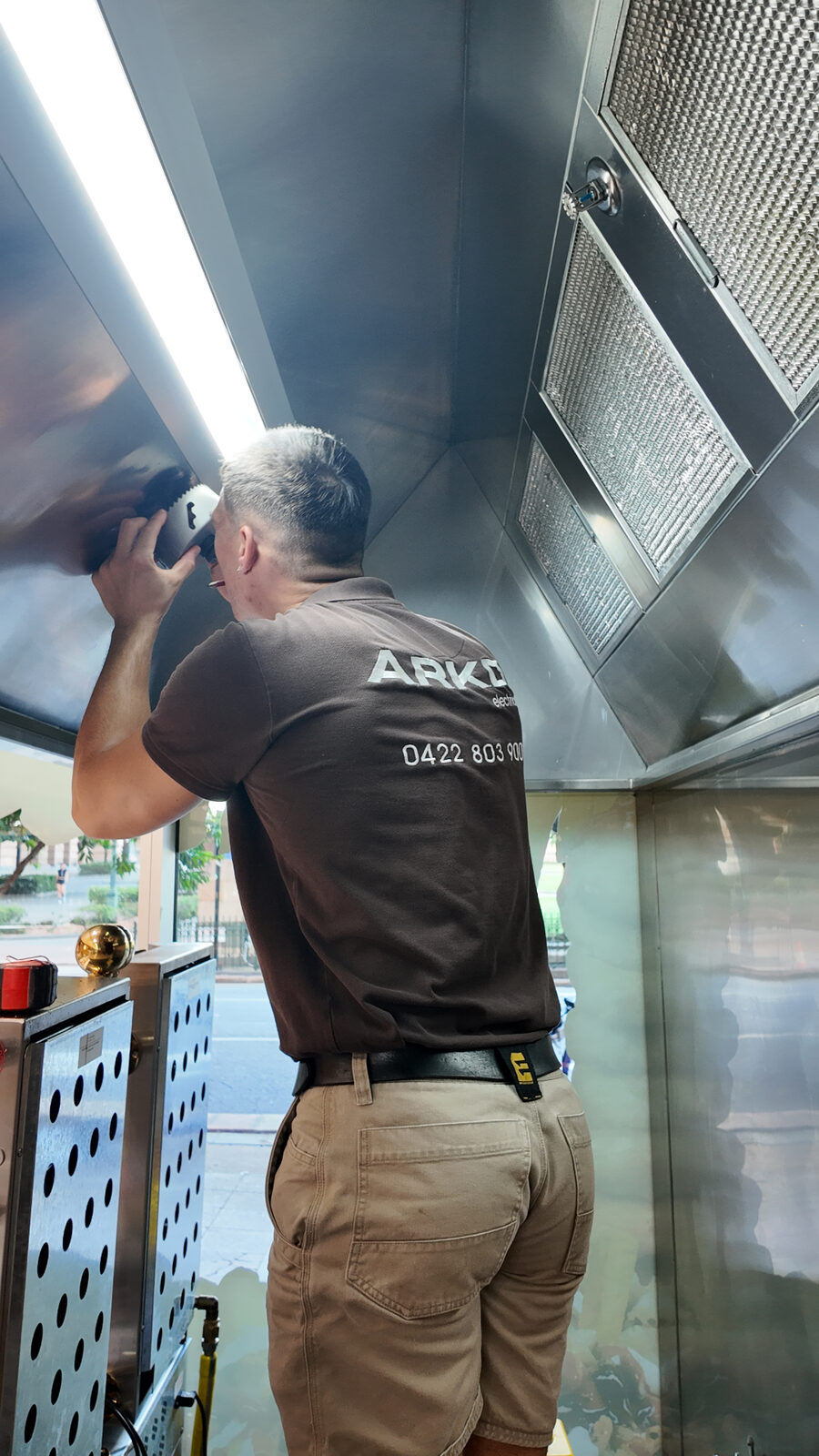ARKD Electrical commercial electrician servicing a stainless steel kitchen exhaust hood in Brisbane